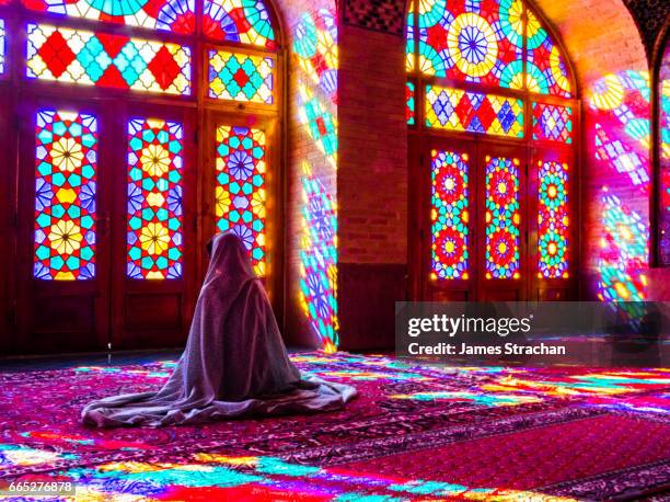 worshipper in front of stained glass windows of prayer hall, nasir-al molk mosque, shiraz, iran - irán fotografías e imágenes de stock