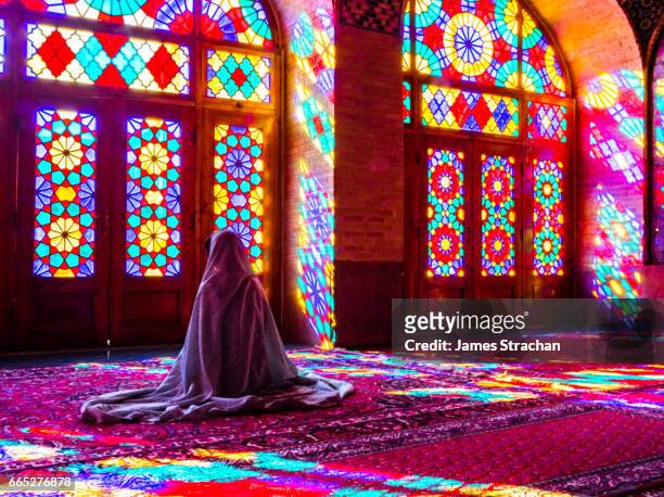 worshipper in front of stained glass windows of prayer hall, nasir-al molk mosque, shiraz, iran - religion stockfoto's en -beelden