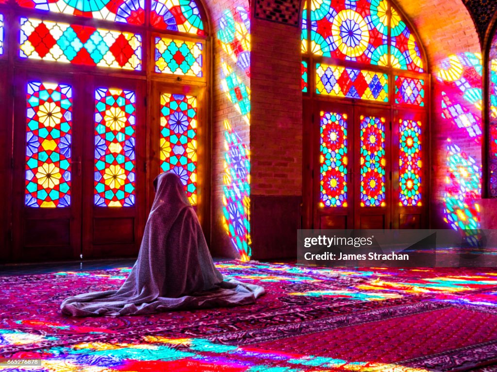 Worshipper in front of stained glass windows of Prayer Hall, Nasir-al Molk Mosque, Shiraz, Iran
