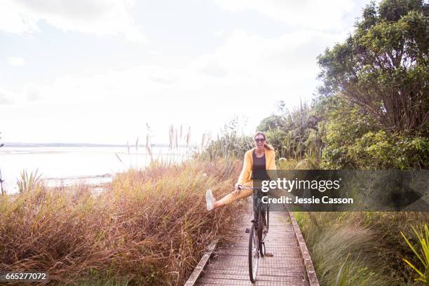 woman on bike with legs apart off pedals - fietsen genieten stockfoto's en -beelden