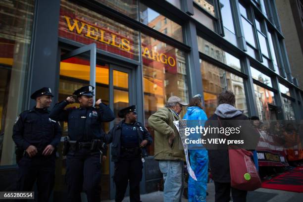 Officers exit the Wells Fargo bank as indigenous peoples and activists begin the overnight camp out in front of the branch on April 5, 2017 in Soho,...