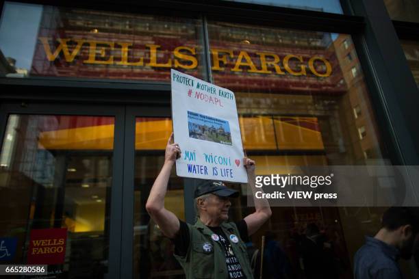 An activist holds a placard at the entrance of Wells Fargo bank as activists begin the overnight camp out in front of the bank on April 5, 2017 in...