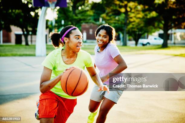 basketball player dribbling ball past defender - sports activity stock-fotos und bilder