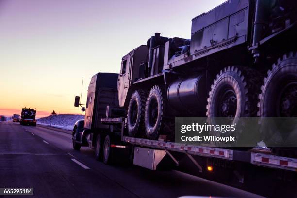 expressway flatbed semi truck convoy hauling armored military land vehicles - moving after stock pictures, royalty-free photos & images