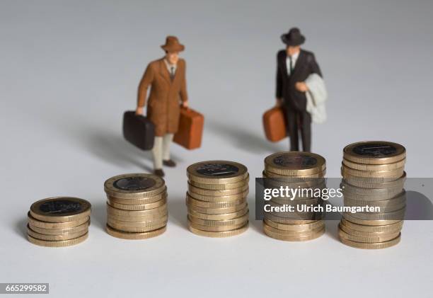 The managers, their salaries and other remunerations. The symbol photo shows several, differently high stacks of one euro coins and two miniature...