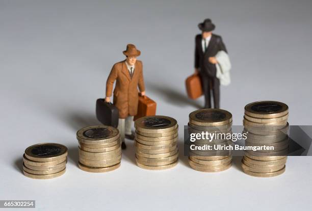 The managers, their salaries and other remunerations. The symbol photo shows several, differently high stacks of one euro coins and two miniature...