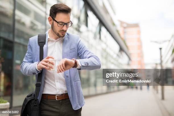 empresario comprobar la hora en su reloj de pulsera - puntualidad fotografías e imágenes de stock