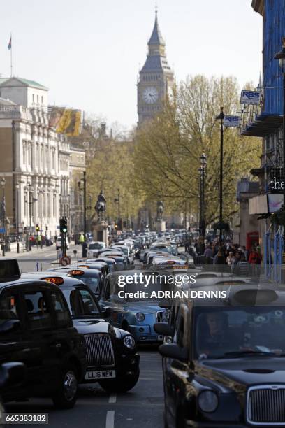 London's black cab drivers block Whitehall during a demonstration over the regulation private hire cars using the Uber app in London on April 6,...