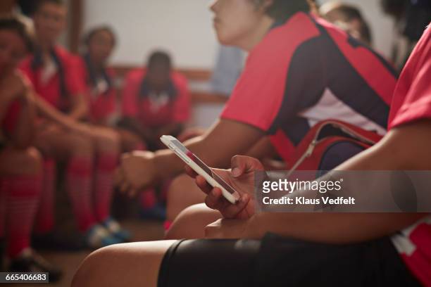 rugby player checking phone in changing room - rugby sport stock-fotos und bilder