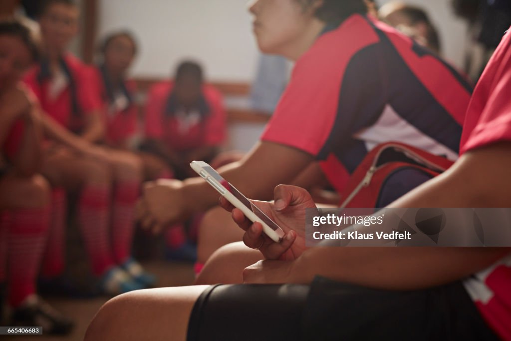 Rugby player checking phone in changing room