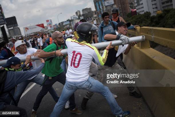 Venezuelan opposition activists breaking part of the highway barrier during clashes wiht Police in Caracas on April 6, 2017. The center-right...