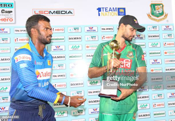 Sri Lanka's cricket captain Upul Tharanga and Bangladesh's cricket captain Mashrafe Mortaza walk away after posing with the series trophy after the...