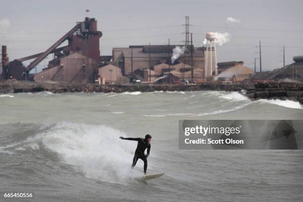 In the shadow of a steel mill, surfers surf the waves of Lake Michigan on April 6, 2017 in Whiting, Indiana. The waves were pushed ashore by...