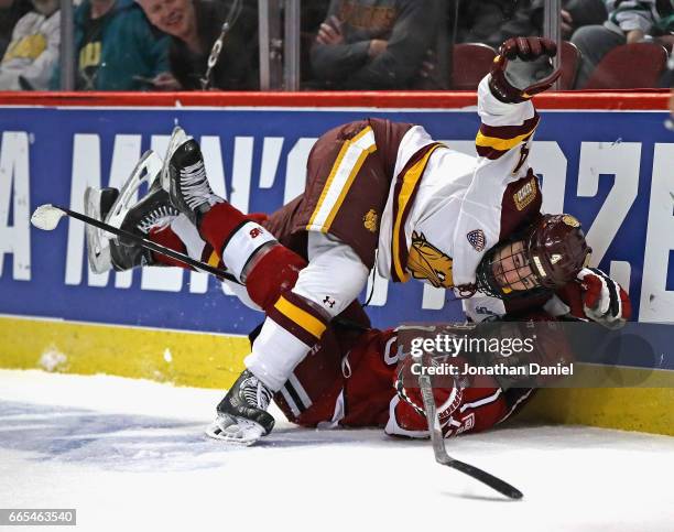 Neal Pionk of the Minnesota-Duluth Bulldogs and Nathan Krusko of the Harvard Crimson get tangled up along the boards during game one of the 2017 NCAA...