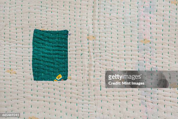 close up of a fabric bedspread or throw, with different fabrics sewn and quilted, a retro style and faded look. one green patch on a cream background. - duvet stock pictures, royalty-free photos & images