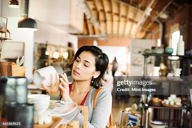 young woman in a shop, looking at a ceramic jug. - indian dish stock pictures, royalty-free photos & images