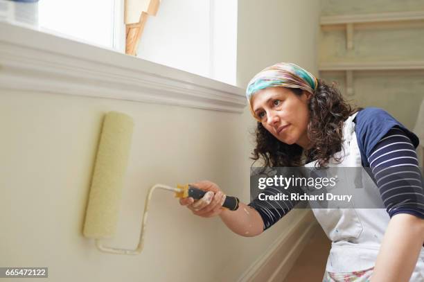female painter and decorator using paint roller - decorator stock pictures, royalty-free photos & images