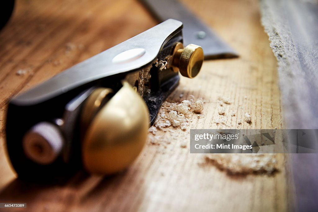 A furniture workshop making bespoke contemporary furniture pieces using traditional skills in modern design. A wood plane with smooth handle and wood shavings.