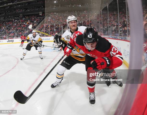 Ben Thomson of the New Jersey Devils is checked by Carter Rowney of the Pittsburgh Penguins during the second period at the Prudential Center on...