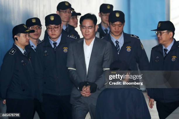 Jay Y. Lee, co-vice chairman of Samsung Electronics Co., center, is escorted by prison officers as he arrives at the Seoul Central District Court in...