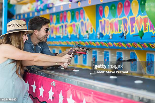 couple at fairground shooting gallery, coney island, brooklyn, new york, usa - fairground stall stock pictures, royalty-free photos & images