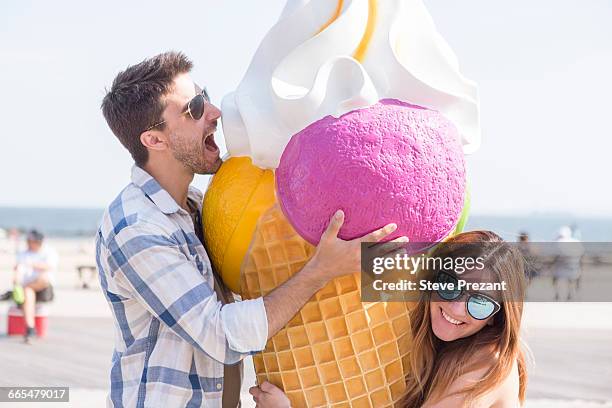 couple on beach with giant ice cream cone, coney island, brooklyn, new york, usa - couple on beach sunglasses stockfoto's en -beelden