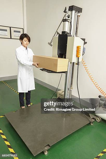 female technician placing cardboard box on packaging machine in printing and packaging factory, china - prepress stock pictures, royalty-free photos & images
