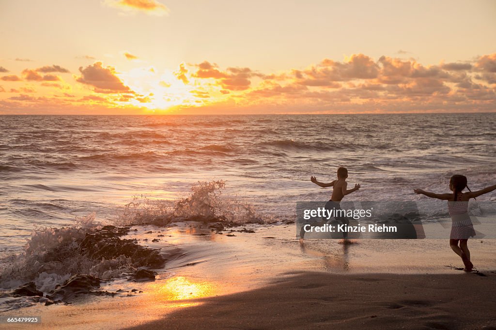 Girl and brother running on beach at sunrise, Blowing Rocks Preserve, Jupiter Island, Florida, USA