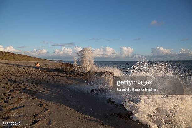 boy watching splashing ocean waves, blowing rocks preserve, jupiter island, florida, usa - blowing rocks preserve stock pictures, royalty-free photos & images