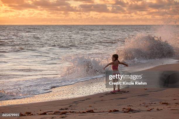 girl with arms open whilst waves splash at sunrise, blowing rocks preserve, jupiter island, florida, usa - blowing rocks preserve stock pictures, royalty-free photos & images