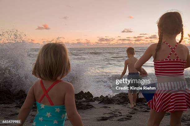 boy and sisters watching splashing waves at sunrise, blowing rocks preserve, jupiter island, florida, usa - blowing rocks preserve stock pictures, royalty-free photos & images