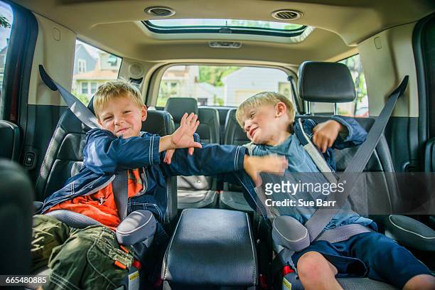 twin brothers sitting in back of vehicle, fighting - children misbehaving stock pictures, royalty-free photos & images