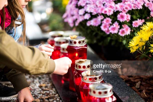 kinder und kerzen am grab - funeral grief flowers stock-fotos und bilder
