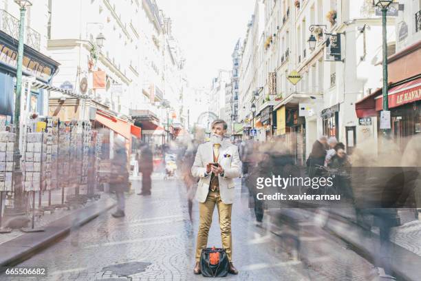 businessman standing amidst crowd moving on street - women smartphone city paris stock pictures, royalty-free photos & images