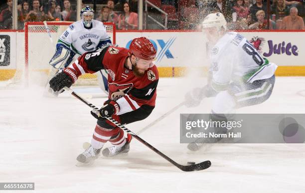 Max Domi of the Arizona Coyotes skates with the puck in front of Nikita Tryamkin of the Vancouver Canucks during the third period at Gila River Arena...