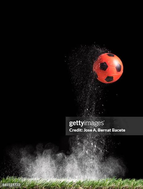 ball of  soccer ball bouncing on a surface of  grass with a cloud of powder for the impact - partícula stock-fotos und bilder