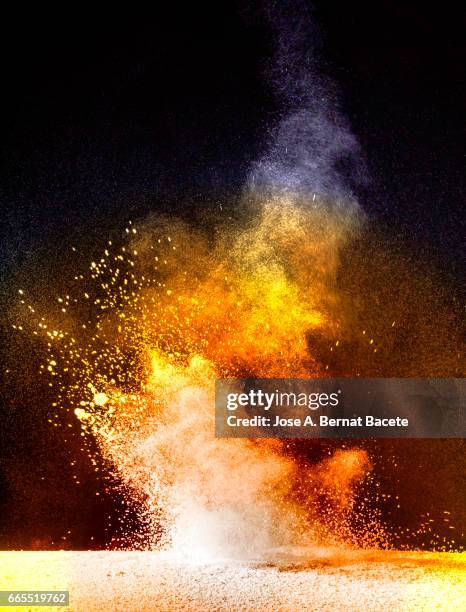 explosion of a cloud of powder of particles of orange color on a black background - partícula stock pictures, royalty-free photos & images