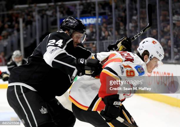 Derek Forbort of the Los Angeles Kings cross checks Matthew Tkachuk of the Calgary Flames during the third period of a game at Staples Center on...