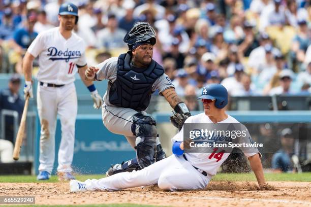 Los Angeles Dodgers left fielder Enrique Hernandez slides safely onto home plate before being tagged by San Diego Padres catcher Hector Sanchez...