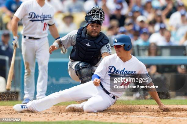 Los Angeles Dodgers left fielder Enrique Hernandez slides safely onto home plate before being tagged by San Diego Padres catcher Hector Sanchez...