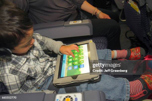 Boy playing a game on an iPad onboard the United Airlines at Miami International Airport.