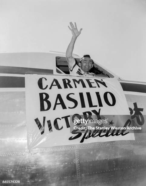 Carmen Basilio waving his hand out of the cockpit from a Mohawk Airlines airplane in Watertown, New York, August 20, 1957.