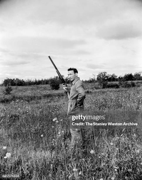 Carmen Basilio standing in a field while bird hunting in Alexandria Bay New York, 1957.