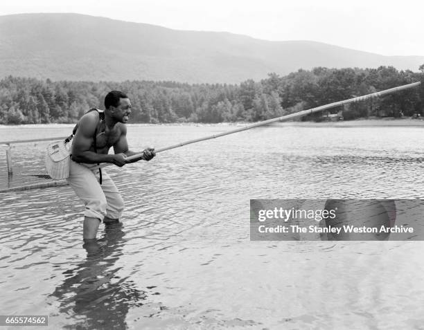 Archie Moore strengthening his forearms by using a bamboo fishing rod at his camp in North Adams, Massachusetts, circa 1955.