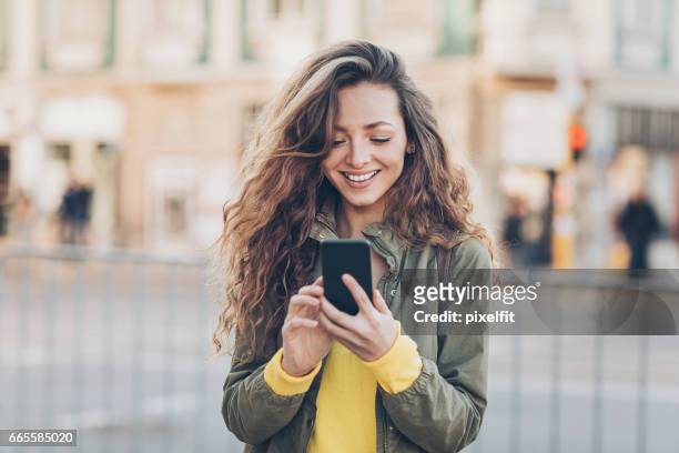 bella ragazza che sms per strada - european spring foto e immagini stock