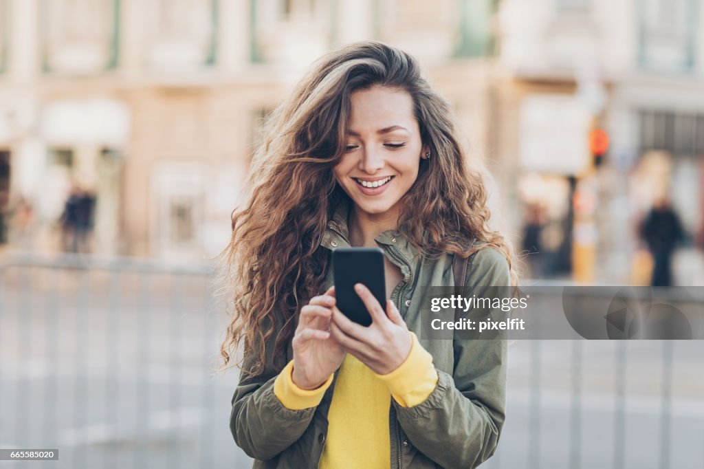 Beautiful girl texting on the street