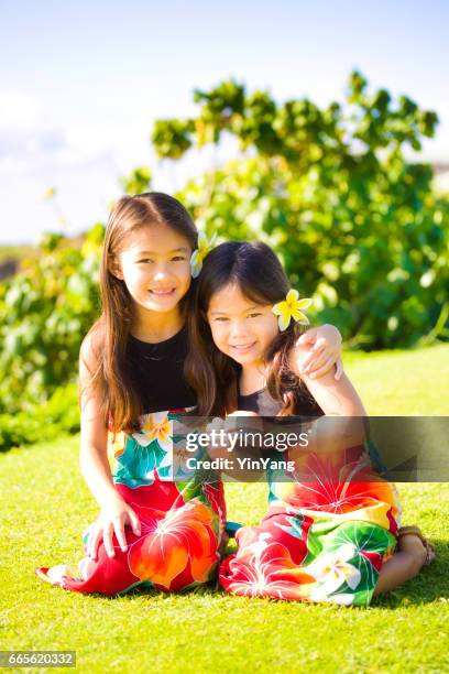 zwei junge mädchen hawaiian polynesische kinder in tradition kleider - fersensitz stock-fotos und bilder