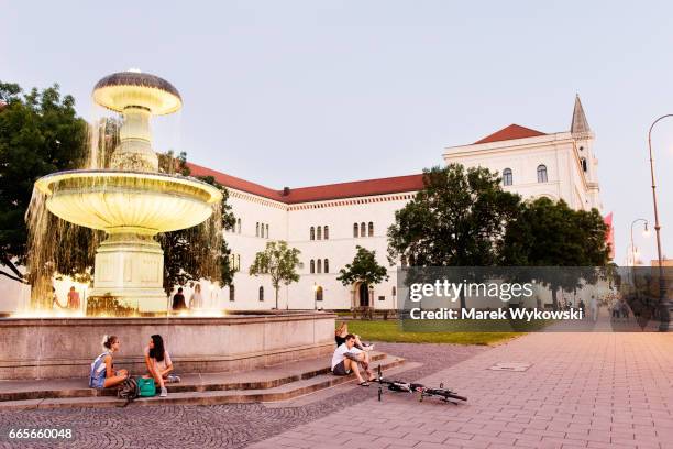 people sitting in at the fountain in front of the munich university (lmu). - munich university stock pictures, royalty-free photos & images