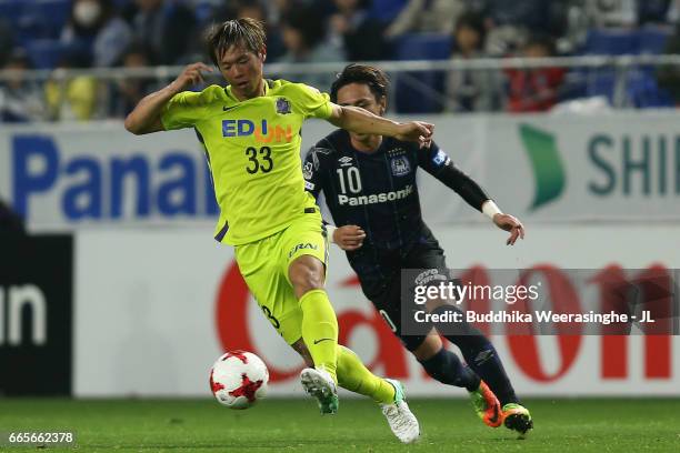 Tsukasa Shiotani of Sanfrecce Hiroshima controls the ball under pressure of Shu Kurata of Gamba Osaka during the J.League J1 match between Gamba...