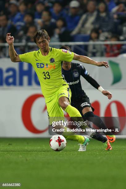 Tsukasa Shiotani of Sanfrecce Hiroshima controls the ball under pressure of Shu Kurata of Gamba Osaka during the J.League J1 match between Gamba...